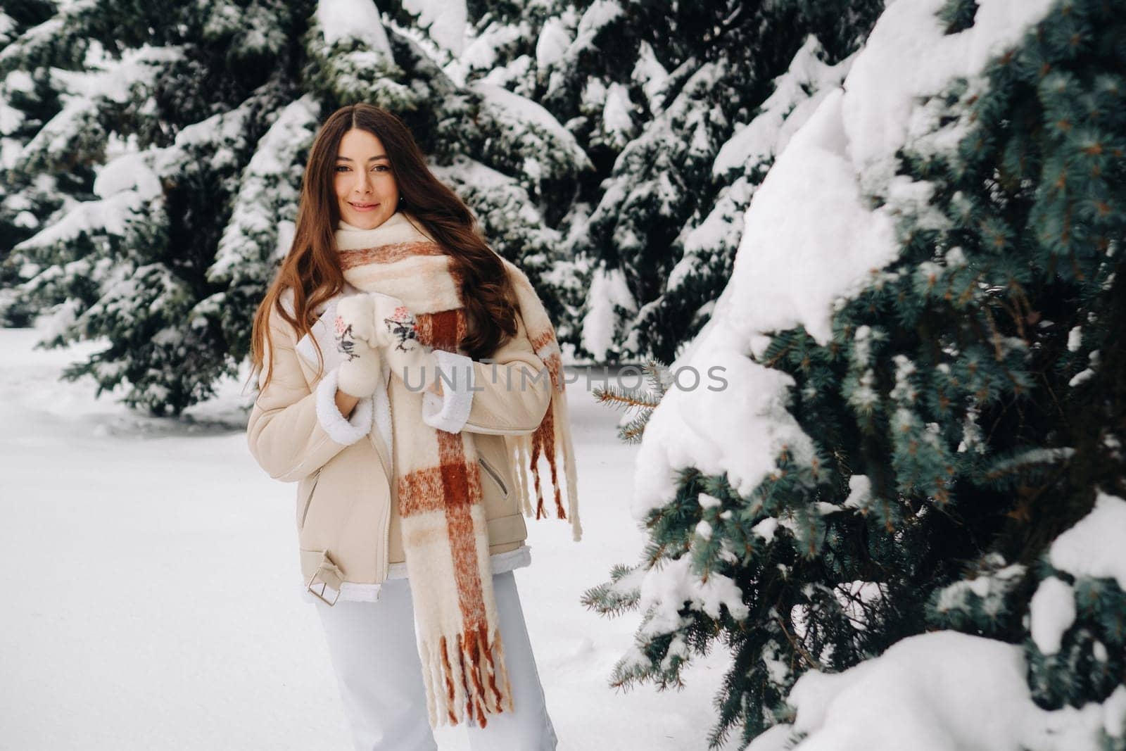 Portrait of a girl with long hair in mittens in a winter forest . Snowy winter.