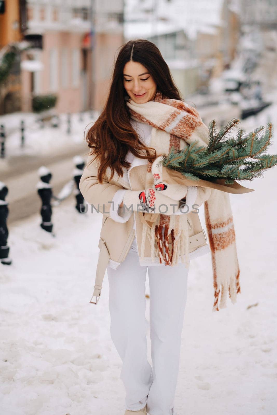 A girl with long hair in winter on the street with a bouquet of fresh fir branches.