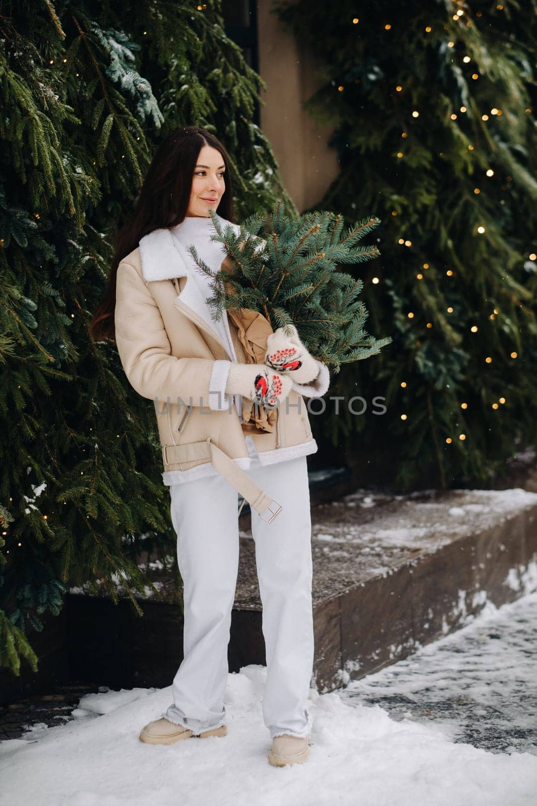 A girl with long hair in winter on the street with a bouquet of fresh fir branches by Lobachad