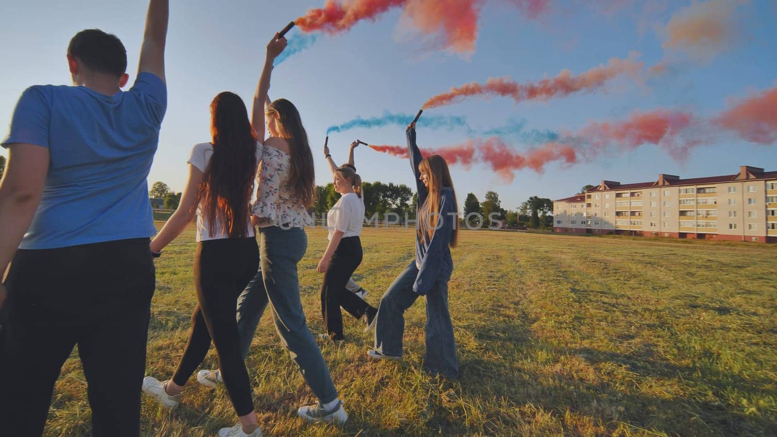 A group of friends spraying multi-colored smoke at sunset. by DovidPro