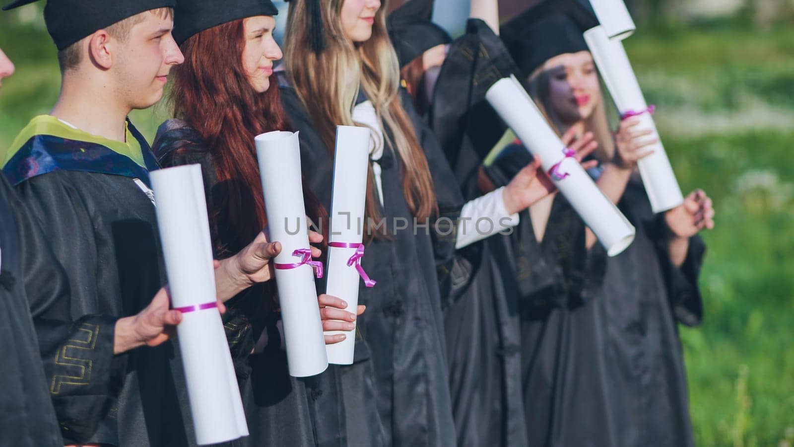 Scrolls of diplomas in the hands of a group of graduates