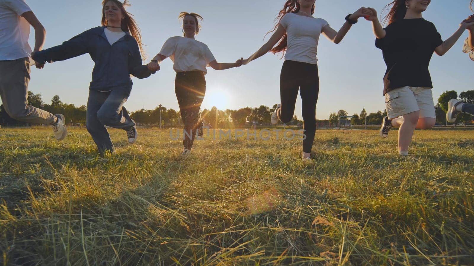 Children running on meadow at sunset