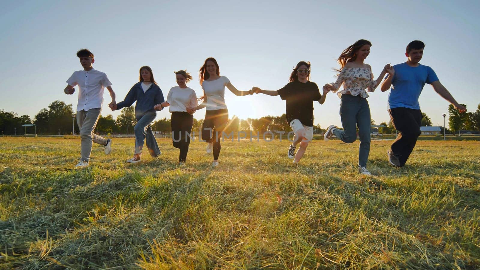 Children running on meadow at sunset. by DovidPro