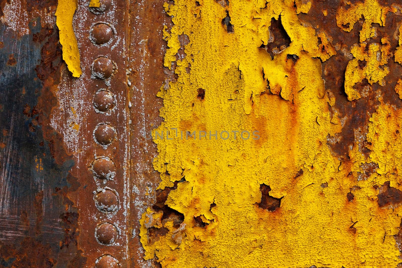 beautifully rusted rivetted sheet metal with leftovers of yellow paint texture and full-frame flat background.