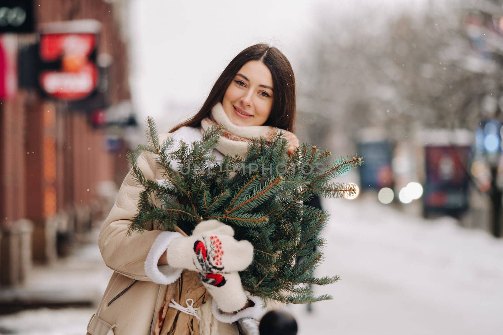Girl with long hair in winter on the street with a bouquet of fresh spruce branches by Lobachad