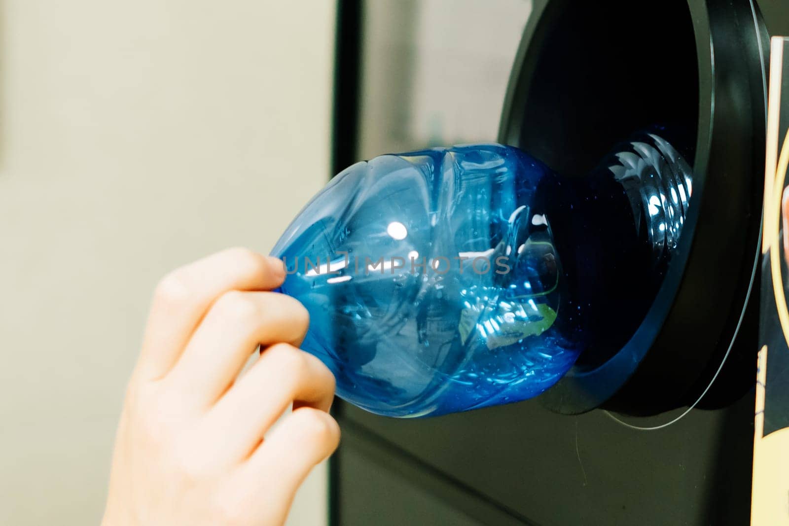 Reverse vending recycling machine that dispenses cash. Man hand puts plastic bottle to the machine by Zelenin