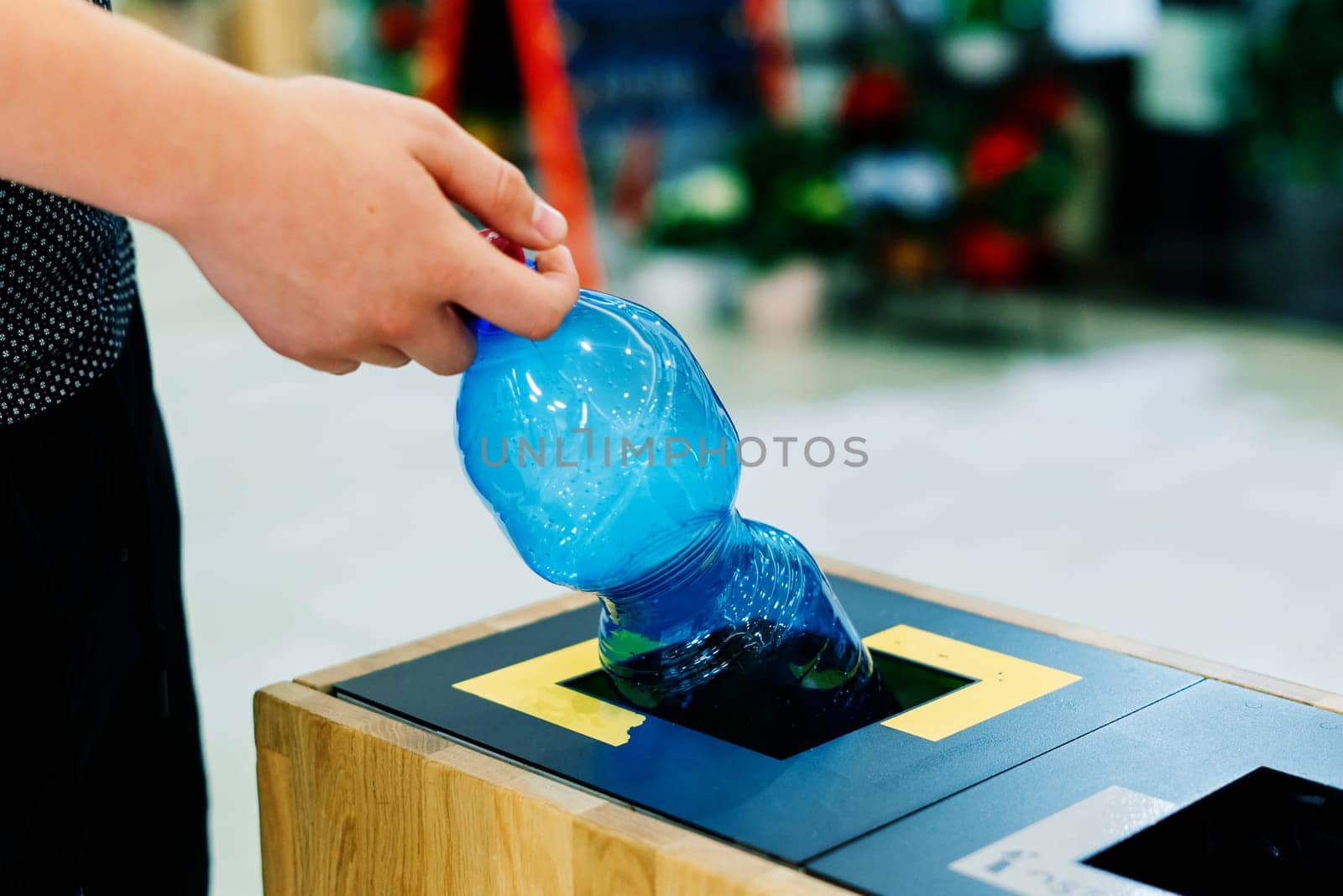 Selective focus close up hand throwing an empty plastic bottle in the recycling garbage trash or bin by Zelenin