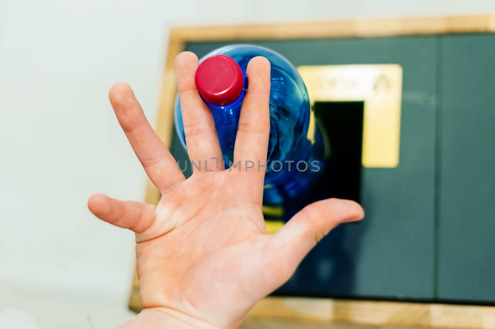 Selective focus close up hand throwing an empty plastic bottle in the recycling garbage trash or bin by Zelenin