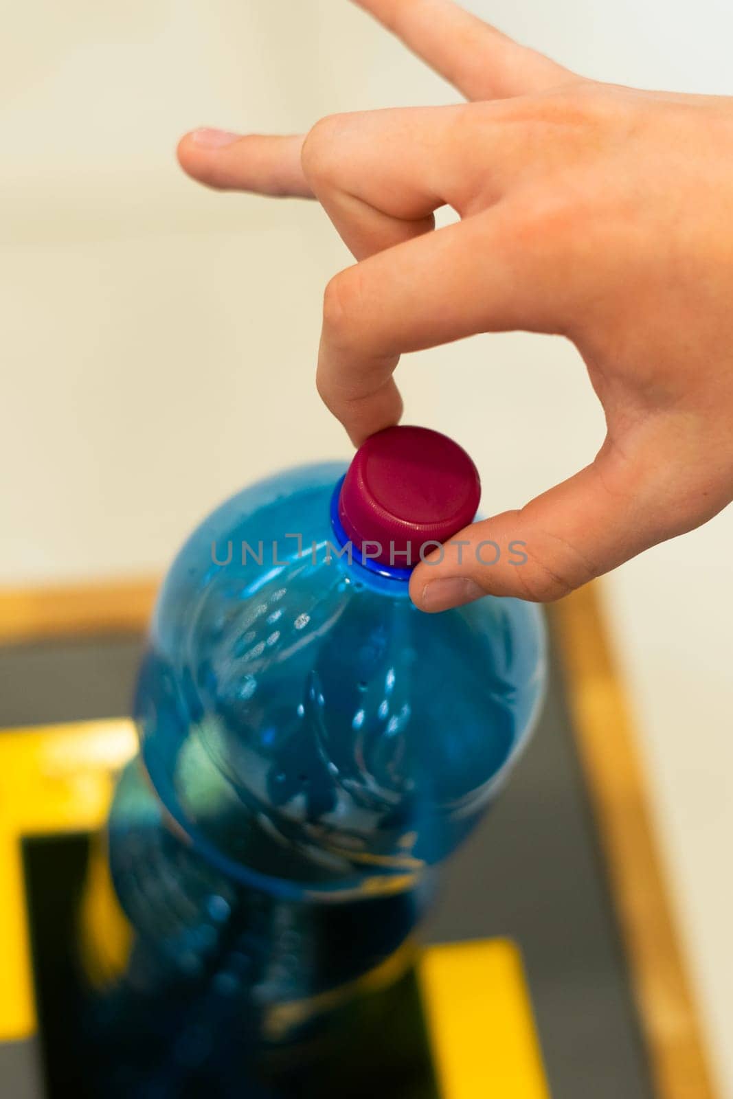 Selective focus close up hand throwing an empty plastic bottle in the recycling garbage trash or bin by Zelenin