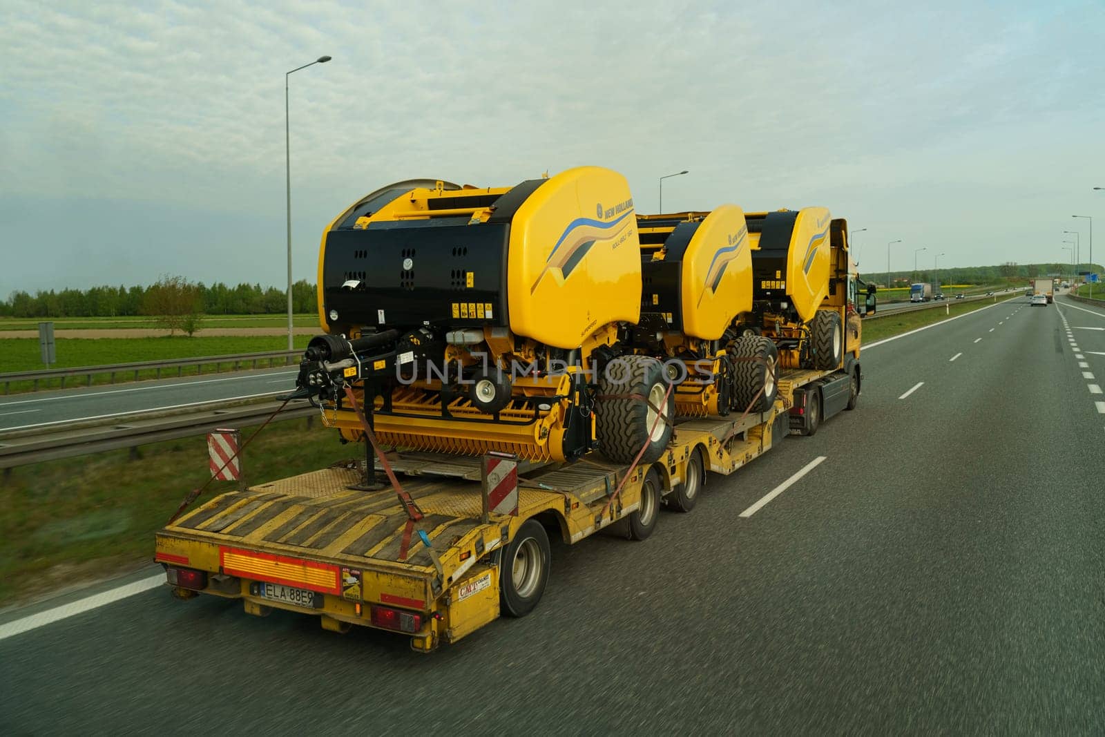 Lubon, Poland - May 5, 2023: A truck transports round balers in a semi-trailer on the highway.