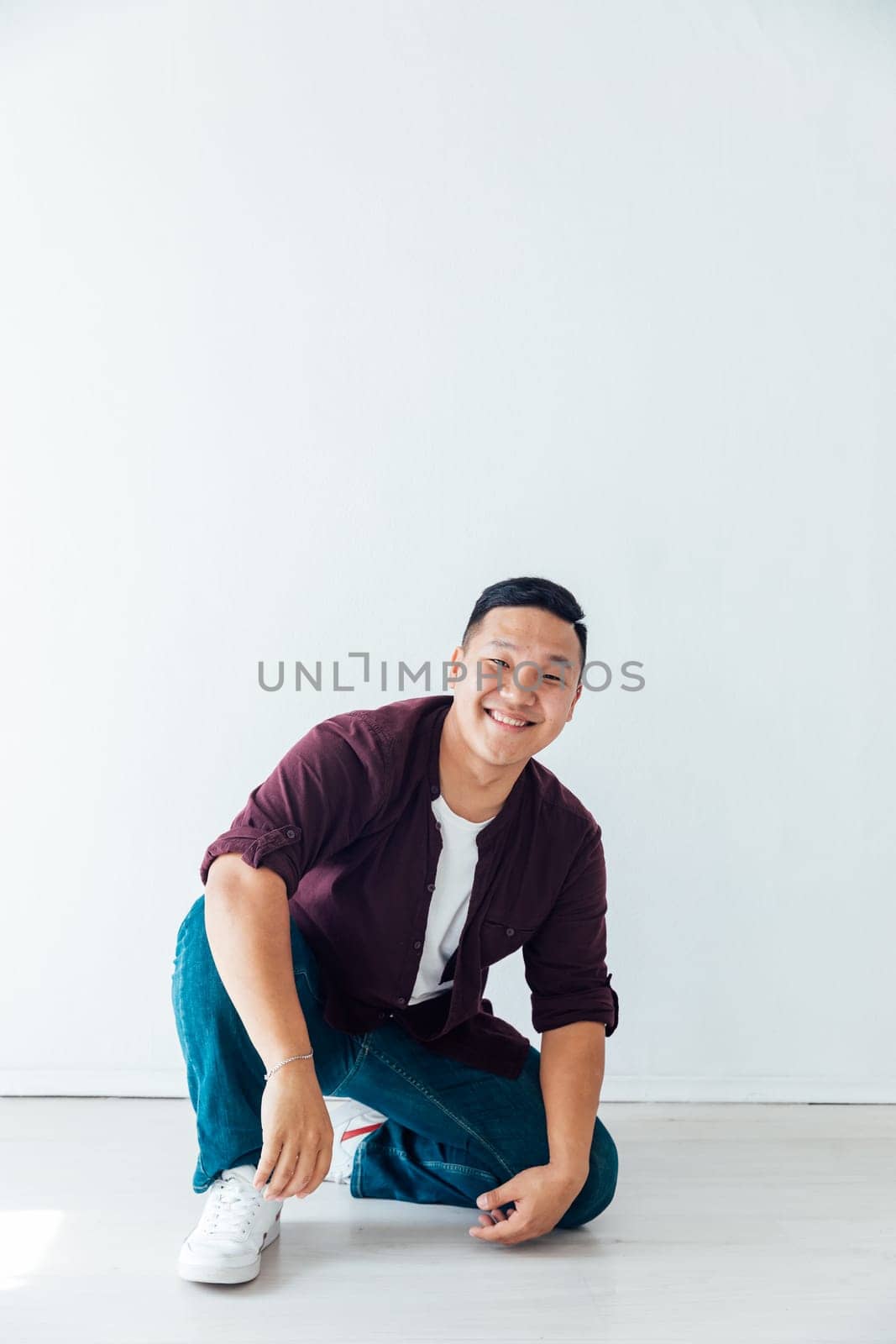 A man sits on the floor on a white background in a studio by Simakov