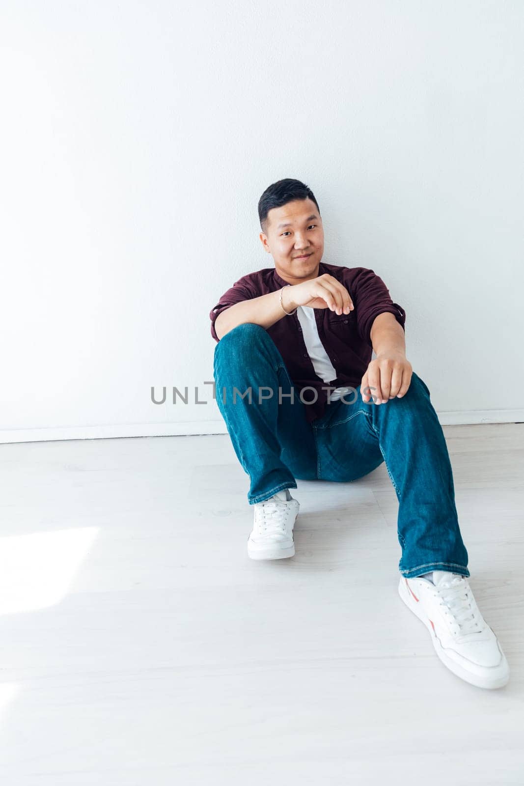 A man sits on the floor on a white background