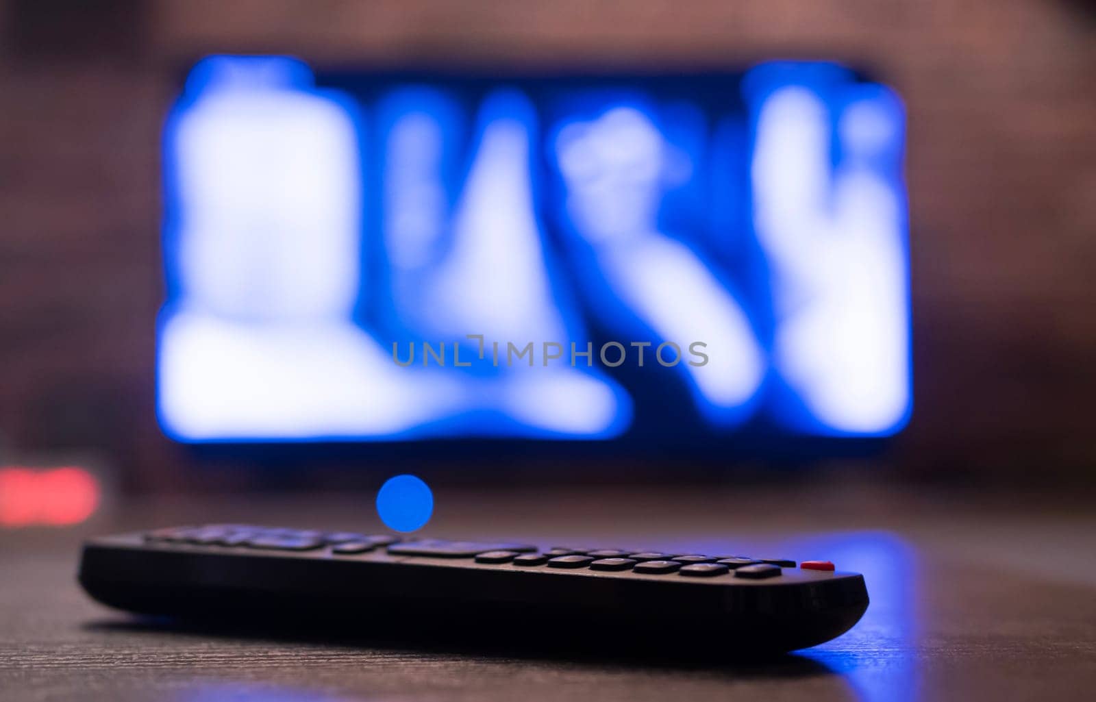 Remote control on a table with a TV on the background. shallow depth of field