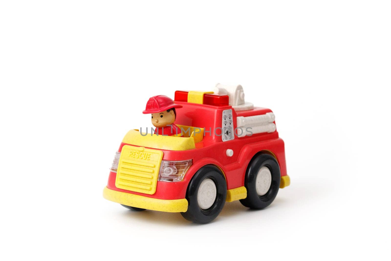 Children's toy red fire truck with driver in the cabin, isolated on whire background.