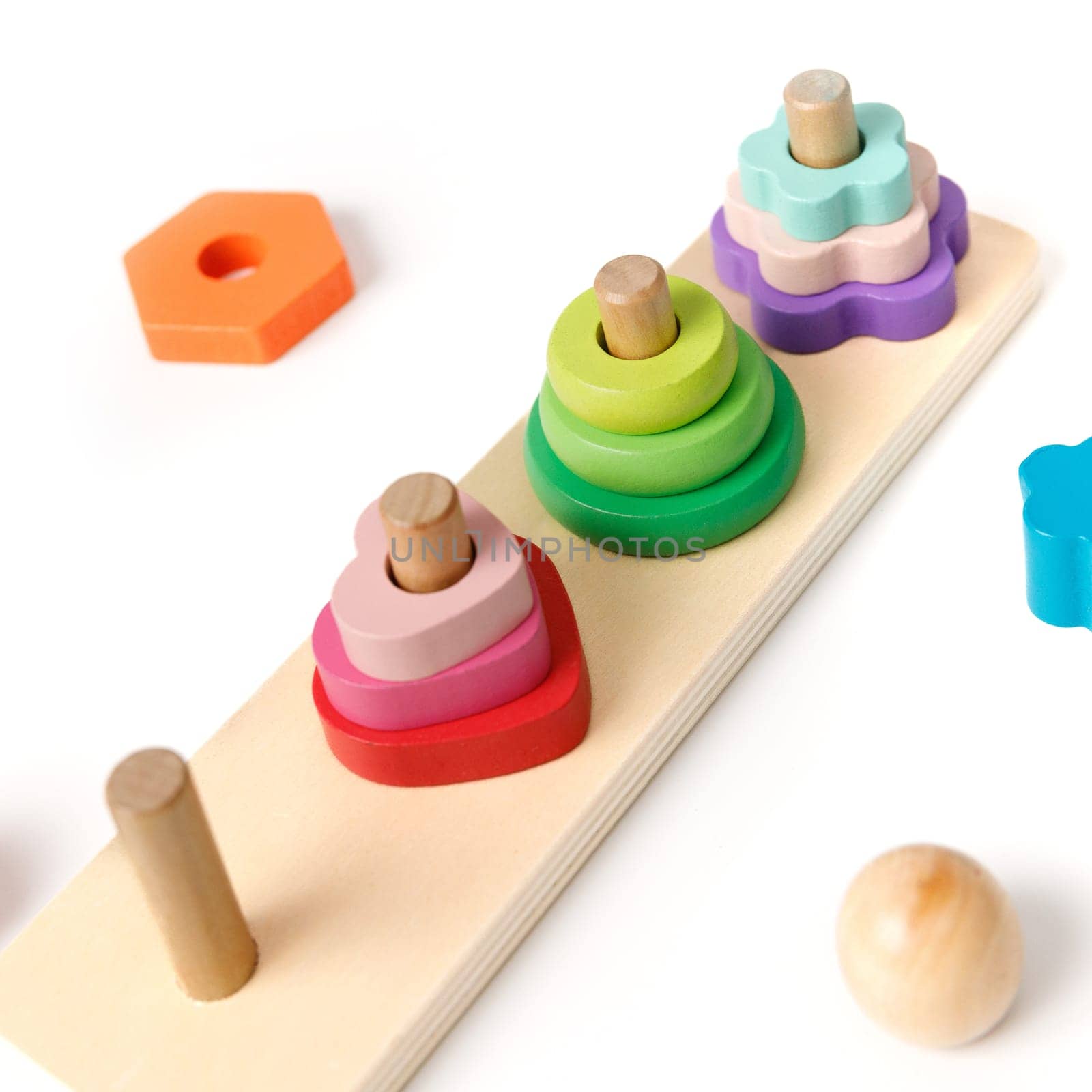 Close-up of Montessori wooden kids's puzzle toy with colorful blocks of different shapes in the shape of 4 pyramids isolated on white background.