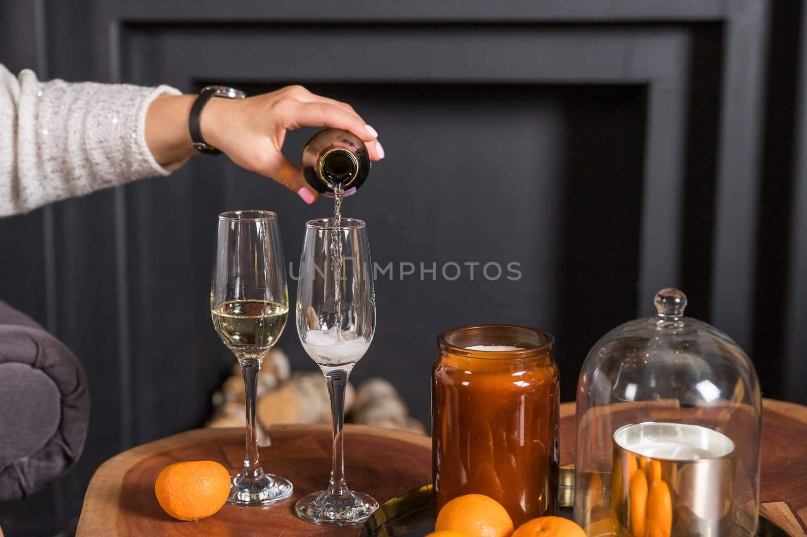 Two glasses of champagne and tangerines on a table against blurred christmas background with christmas lights. New year celebration party