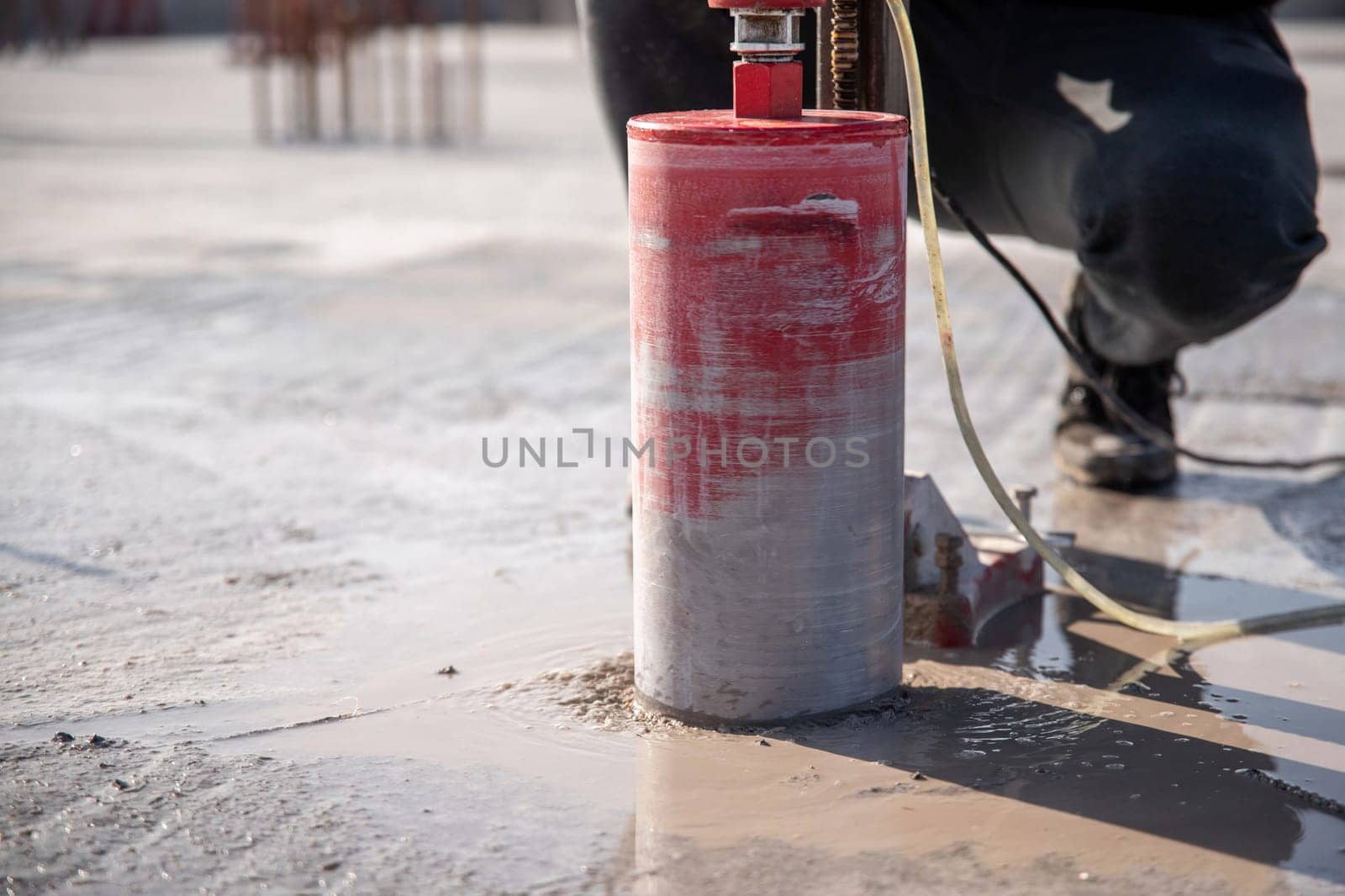 A worker drills a reinforced concrete floor using a drilling rig with a diamond bit by Rom4ek