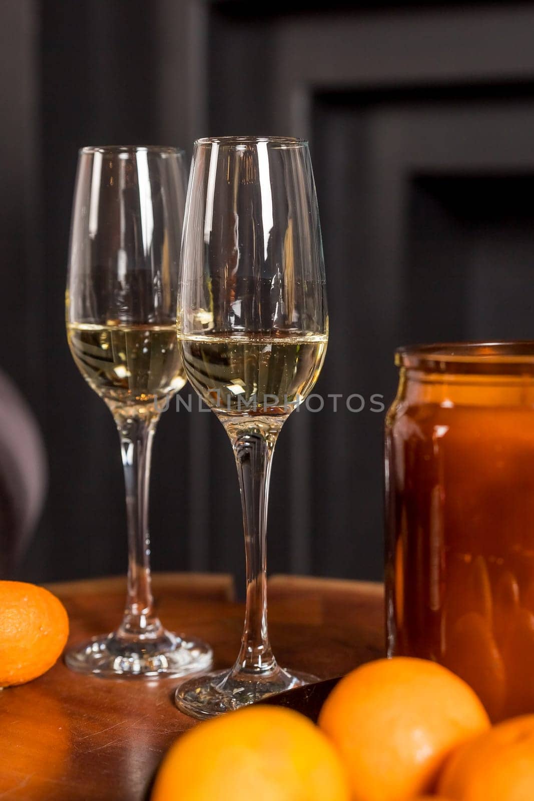 Two glasses of champagne and tangerines on a table against blurred christmas background with christmas lights. New year celebration party