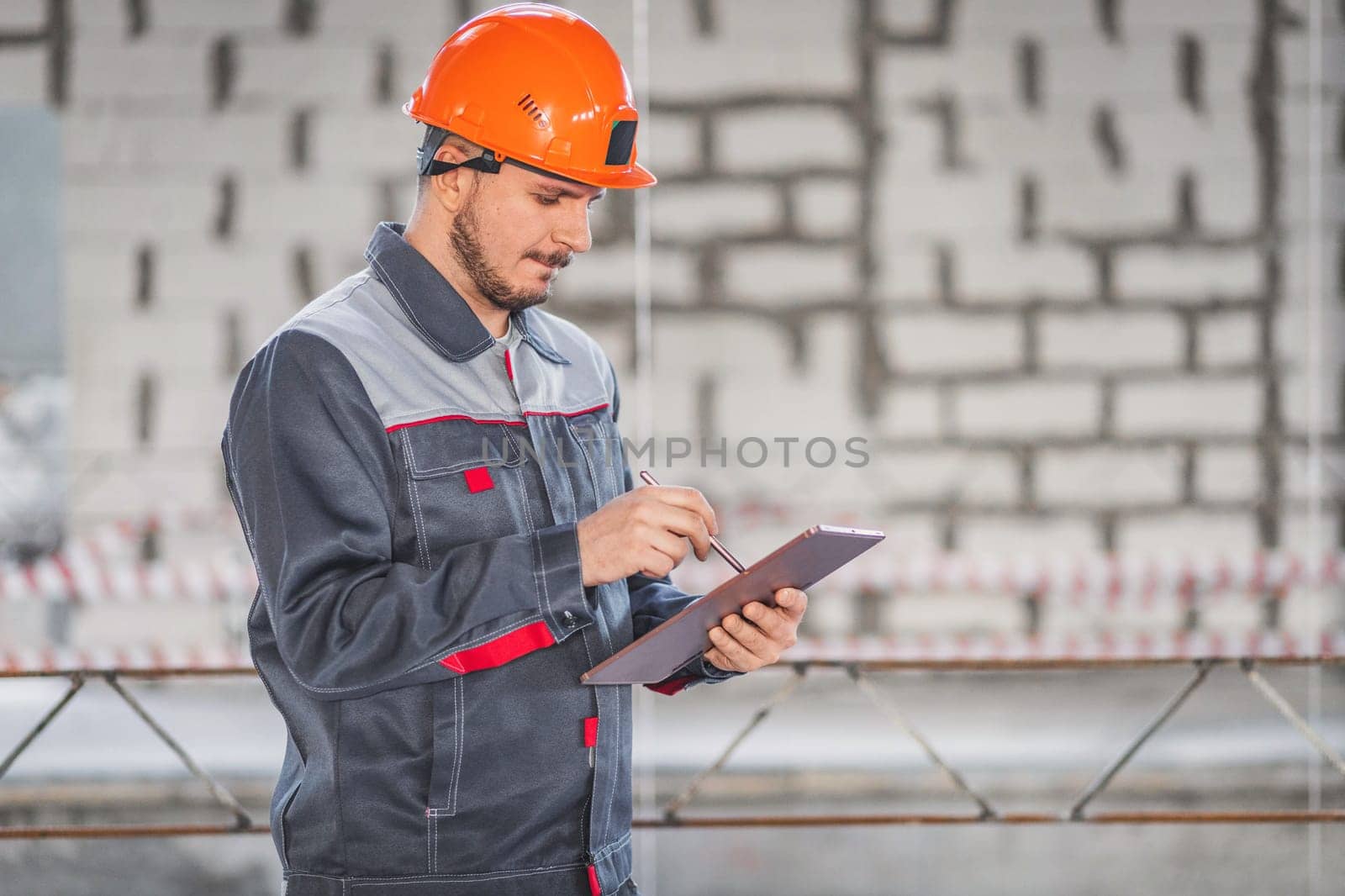 A builder looks at a project on a digital tablet and checks the plans of a house being built on a construction site, copy space.