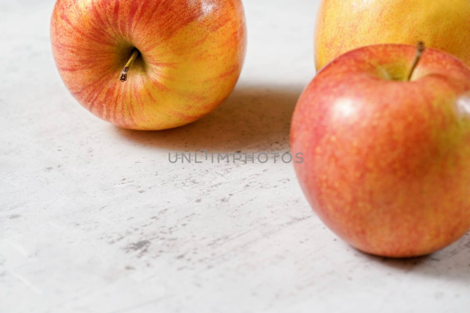 Red and yellow apples (kiku variety) on white board, closeup whit space for text down left. by Ivanko