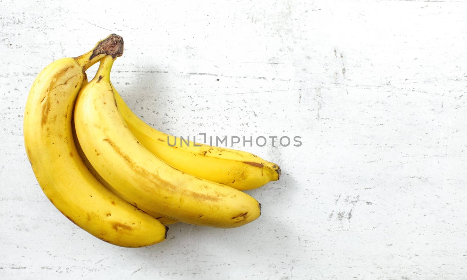 Bunch of bananas on white working board, space for text right by Ivanko