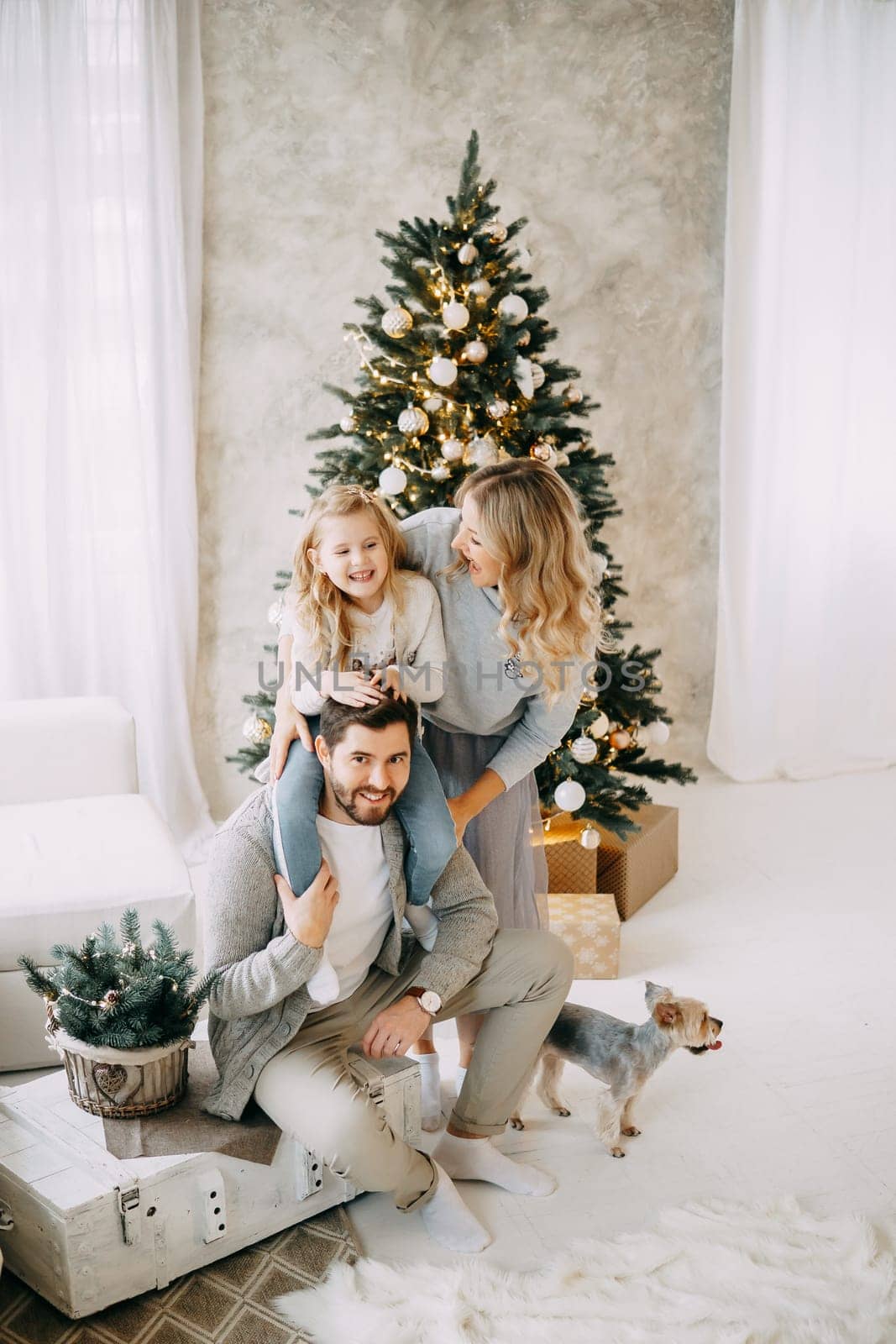 Happy family: mom, dad and daughter. Family in a bright New Year's interior with a Christmas tree