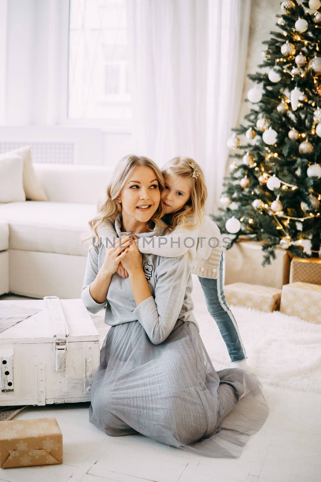 Happy family: mother and daughter. Family in a bright New Year's interior with a Christmas tree