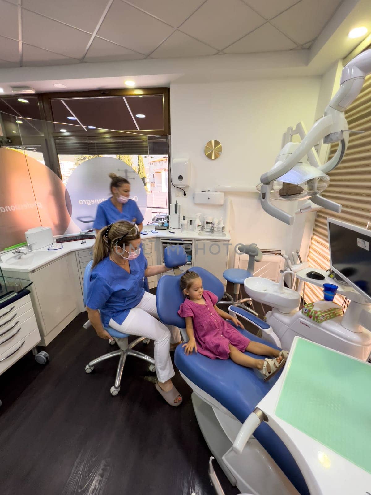 Little girl sitting in the dentist chair next to the doctor. High quality photo