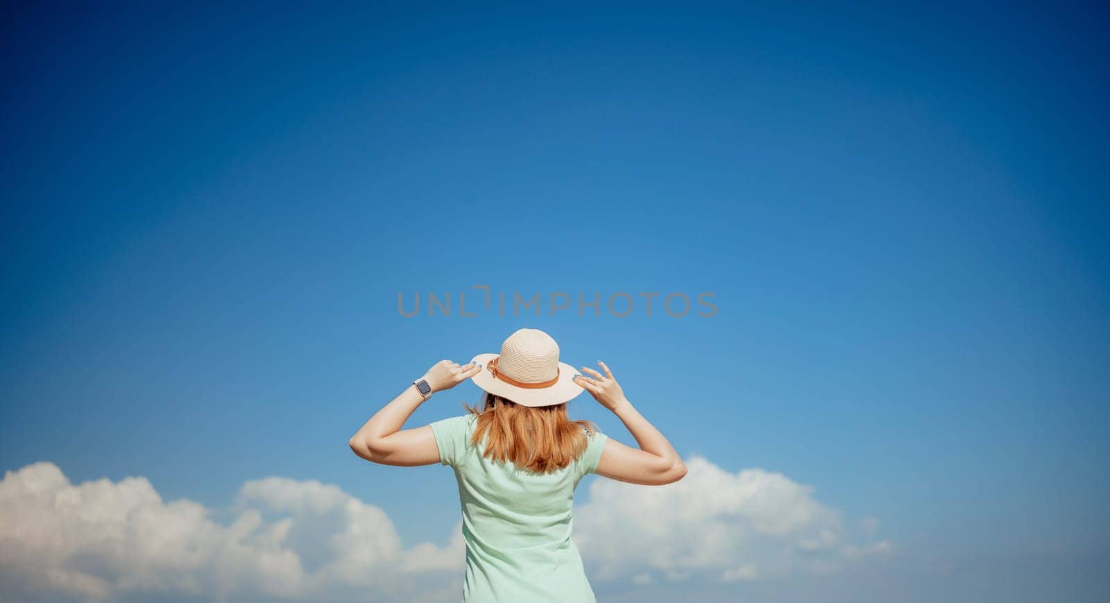Woman tourist sky sea. Happy traveller woman in hat enjoys vacation raised her hands up.