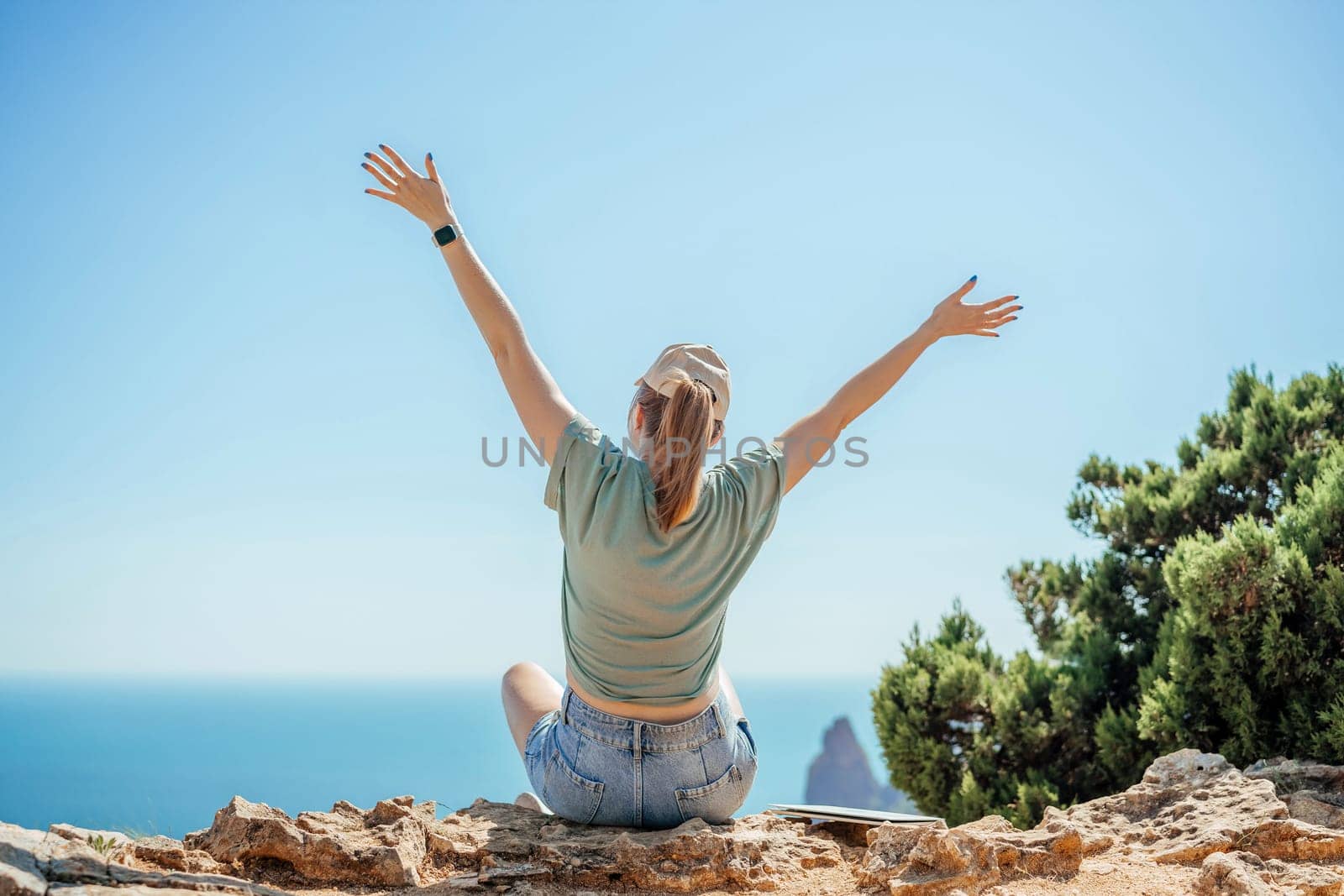 Woman tourist sky sea. Happy traveller woman in hat enjoys vacation raised her hands up.