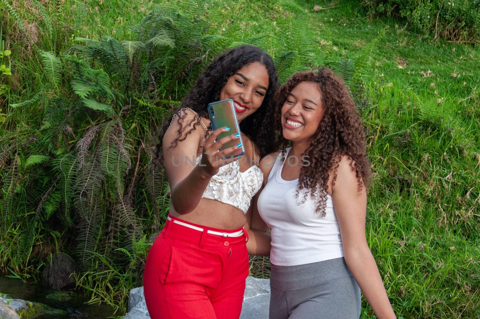 Latina content creators broadcasting live on social media and talking to their followers in a rural setting by Raulmartin