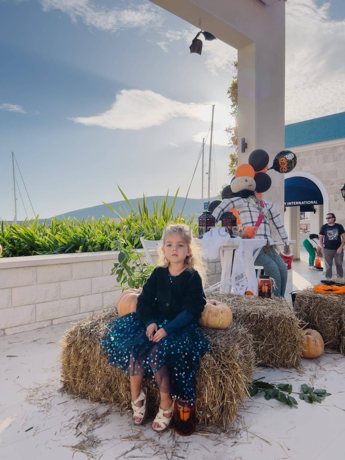 Little girl sits thoughtfully on a haystack near the scenery for Halloween. High quality photo