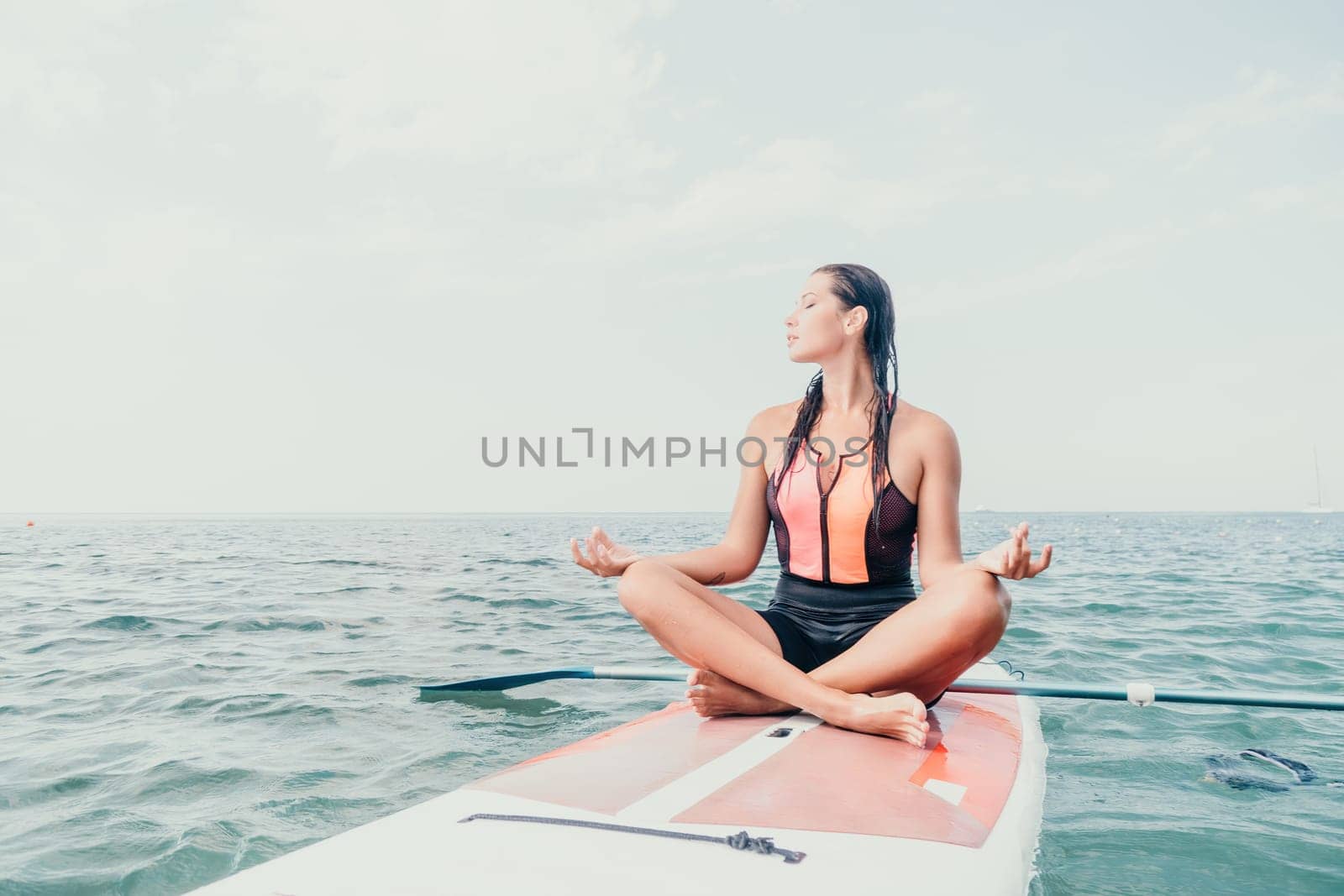 Woman sup yoga. Happy young sporty woman practising yoga pilates on paddle sup surfboard. Female stretching doing workout on sea water. Modern individual female outdoor summer sport activity