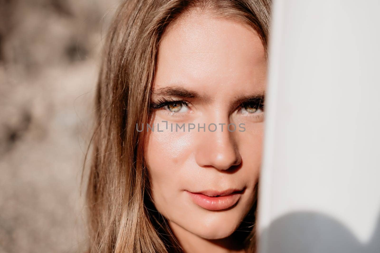 Close up shot of beautiful young caucasian woman with black hair and freckles looking at camera and smiling. Cute woman portrait in a pink bikini posing on a volcanic rock high above the sea