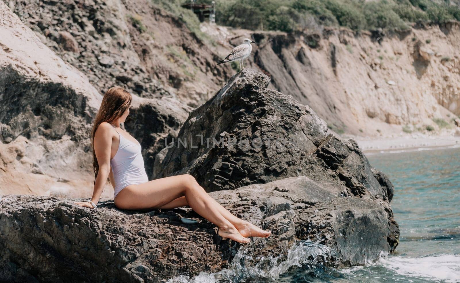 Woman travel sea. Young Happy woman in a long red dress posing on a beach near the sea on background of volcanic rocks, like in Iceland, sharing travel adventure journey