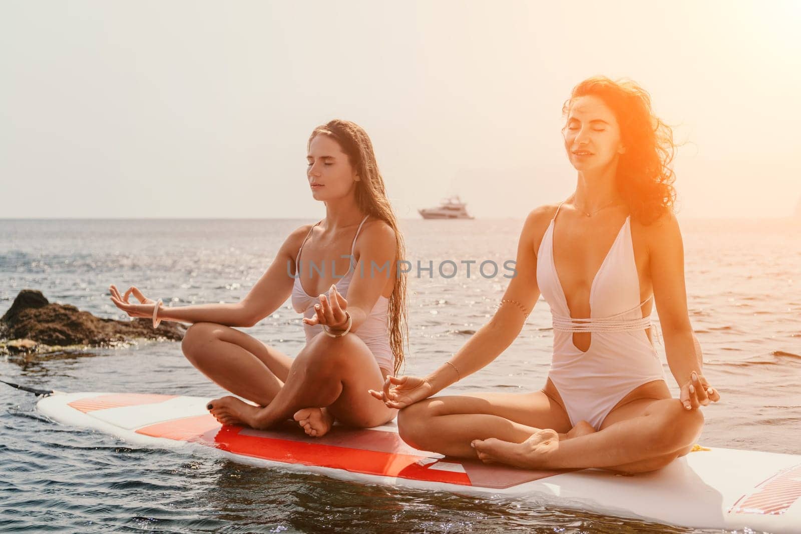 Woman sup yoga. Happy sporty woman practising yoga pilates on paddle sup surfboard. Female stretching doing workout on sea water. Modern individual female hipster outdoor summer sport activity. by panophotograph