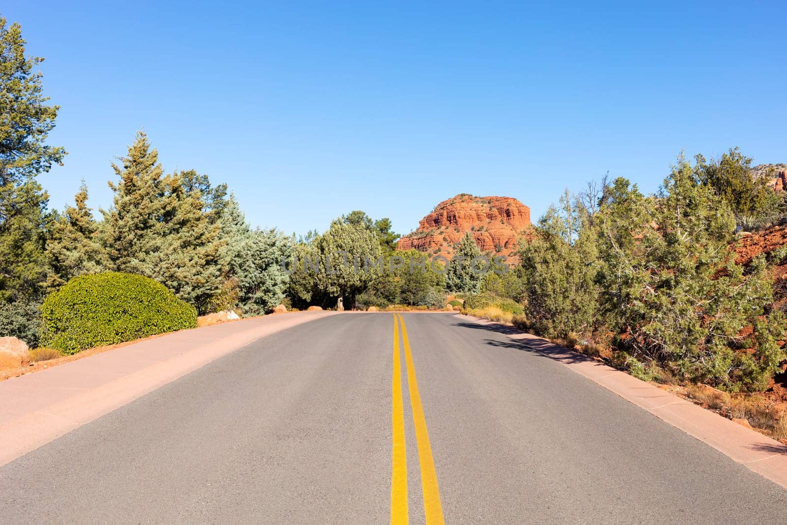 Long Straight Road Leading Towards Red Rock Mountain Butte Of Sedona, Arizona, USA Within Coconino National Forest. Beautiful Scenic Landscape. Attraction, Spiritual Place. Horizontal by netatsi