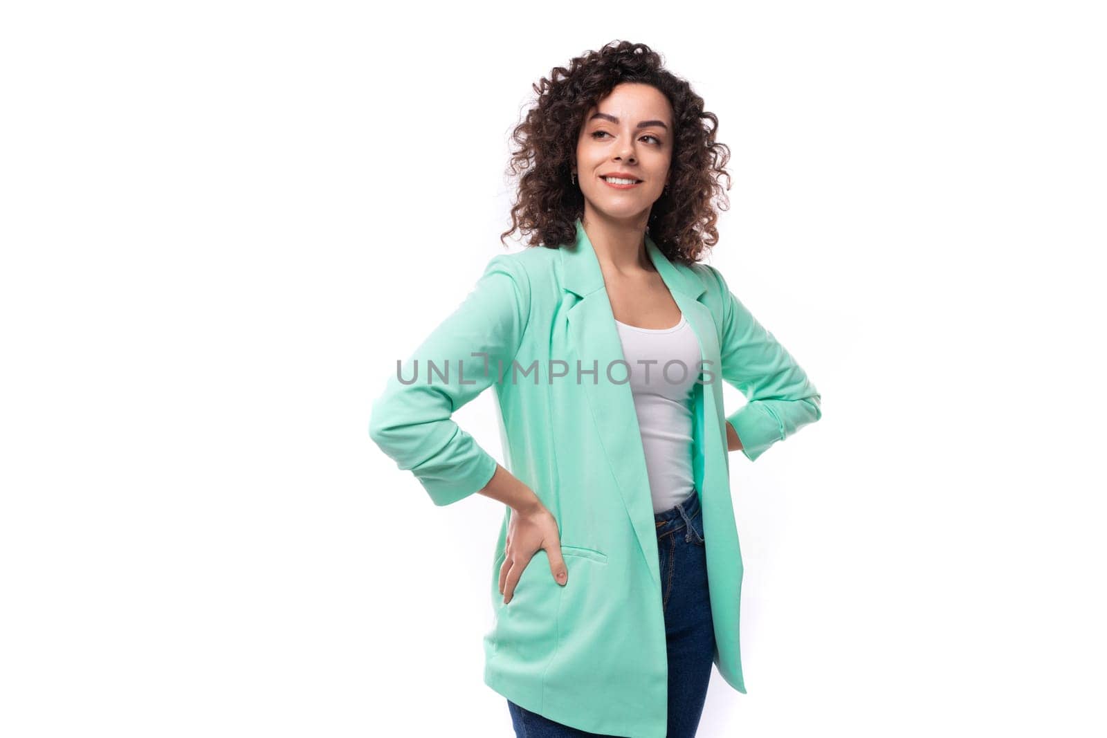 pretty smiling young brunette curly businesswoman dressed in a blue jacket.