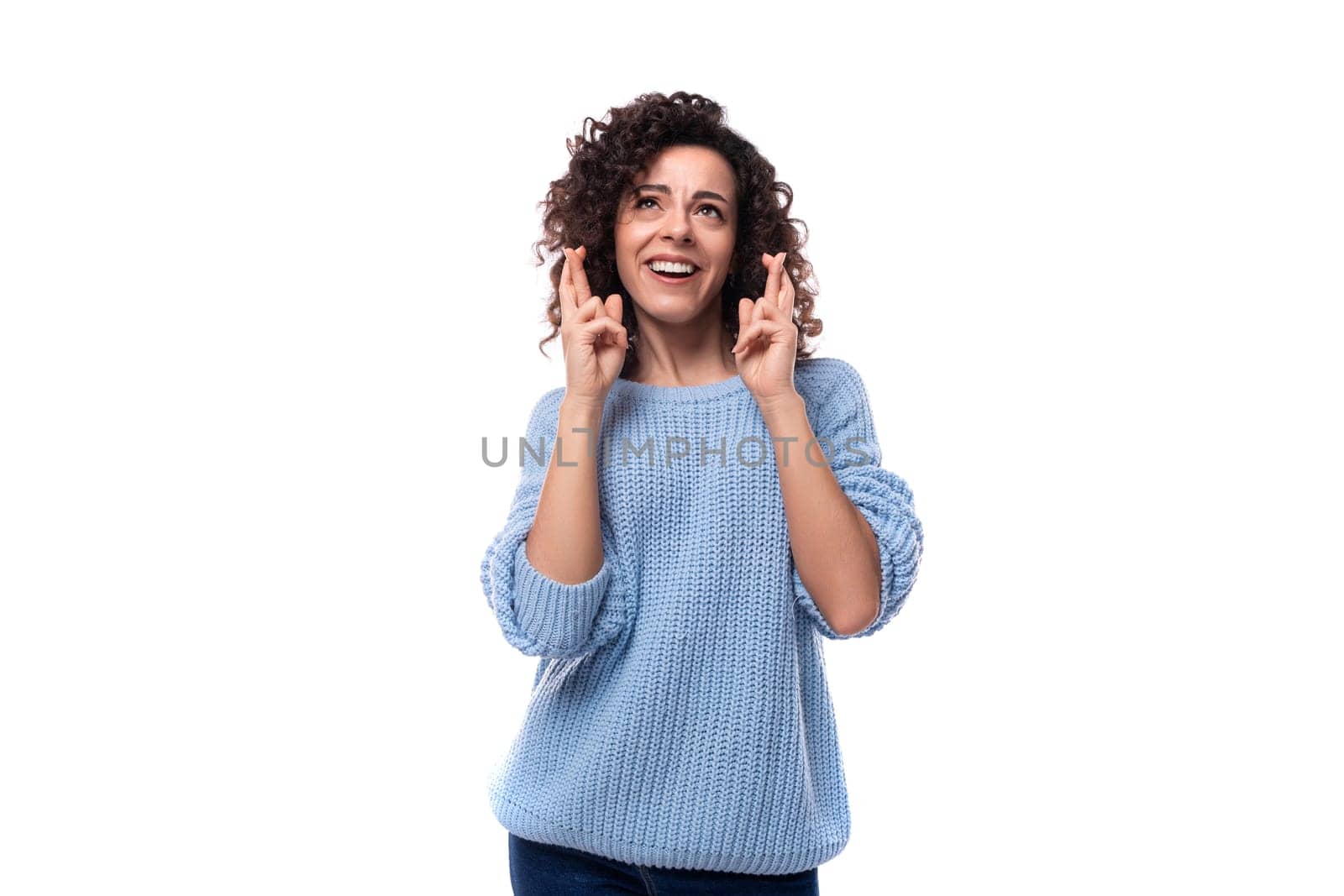 a young pretty lady with black curly hair dressed in a light blue sweater crossed her fingers in anticipation by TRMK
