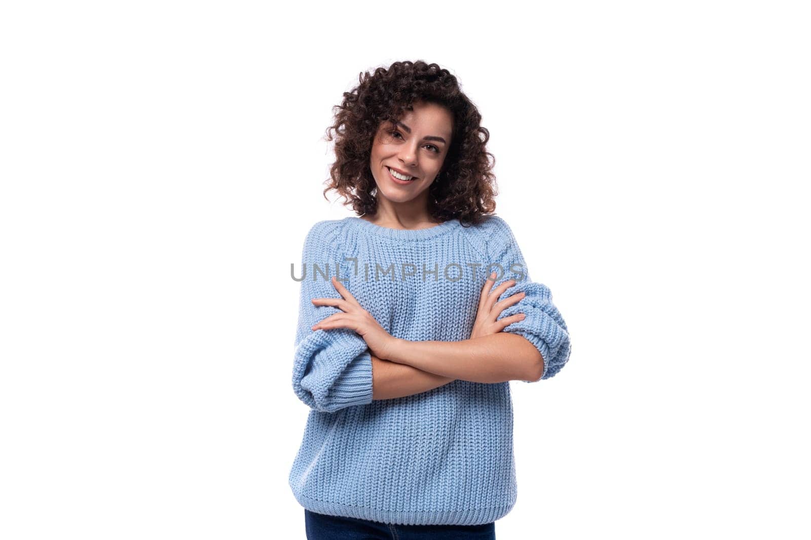 portrait of a young caucasian woman with curly natural dark hair dressed in a casual warm blue jacket.