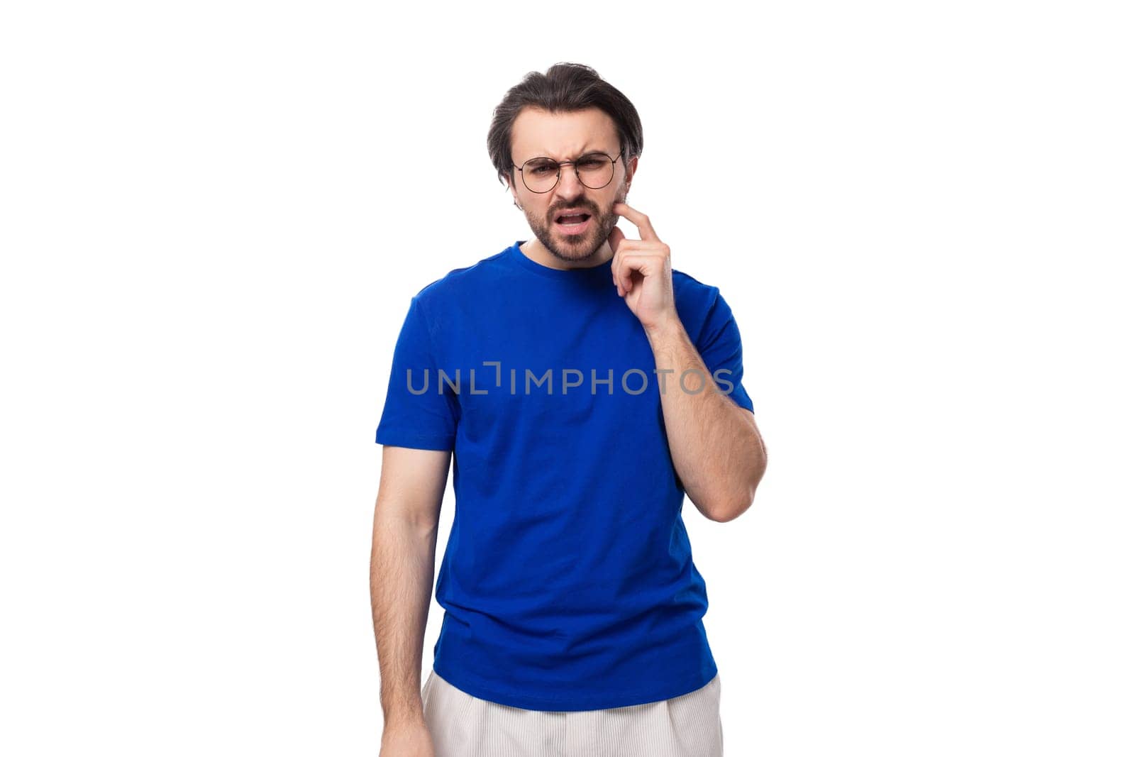 young brutal caucasian brunette man with stylish haircut and beard in blue t-shirt with identity mockup.