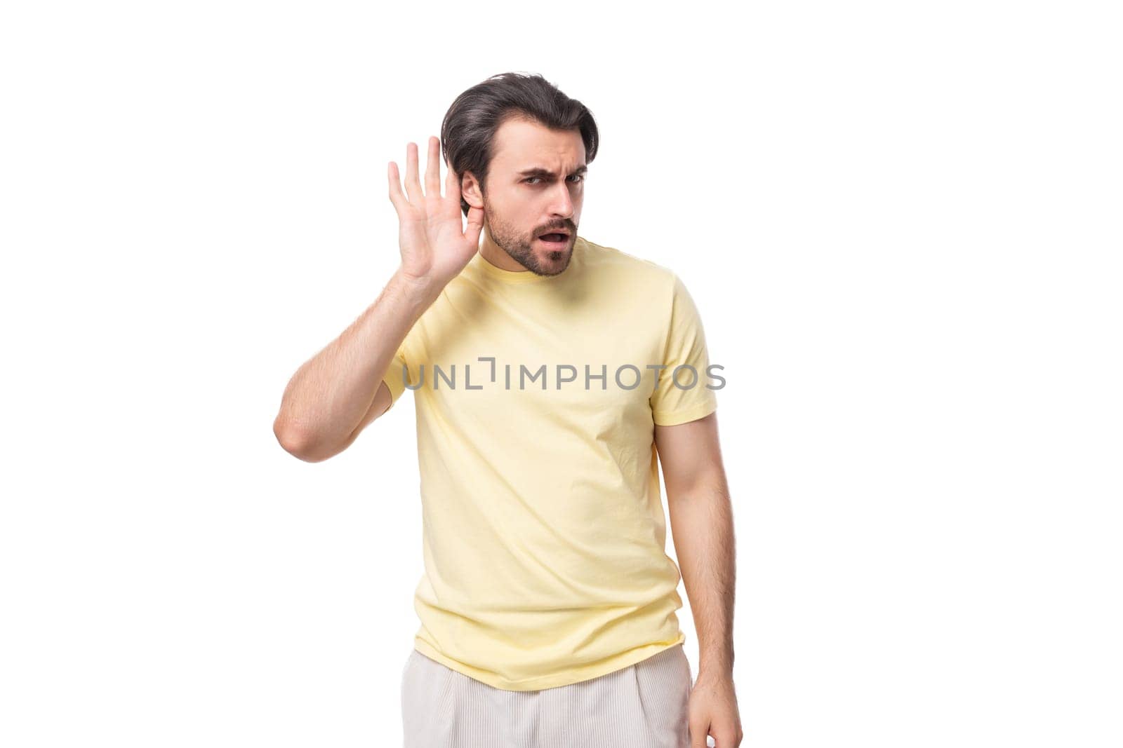 caucasian surprised brutal charming guy with a beard dressed in a summer t-shirt on a white background with copy space by TRMK