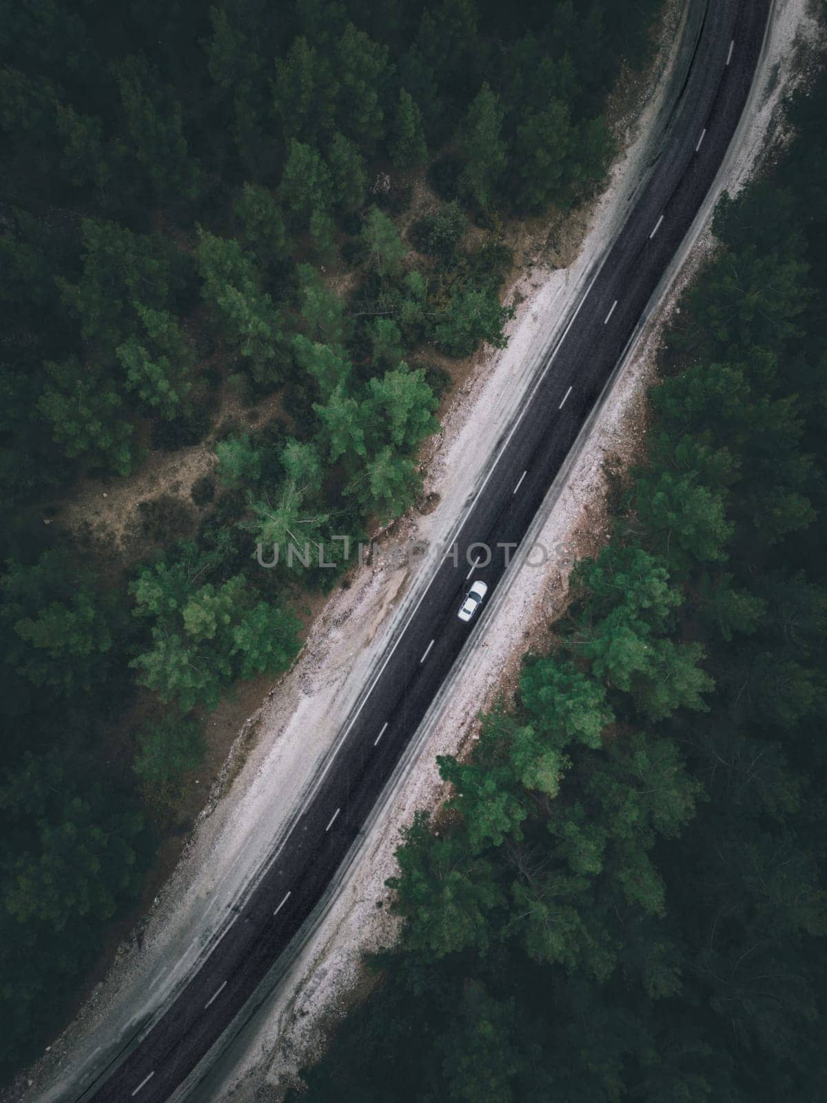 Aerial view taken by drone of a car driving on a forest road in autumn