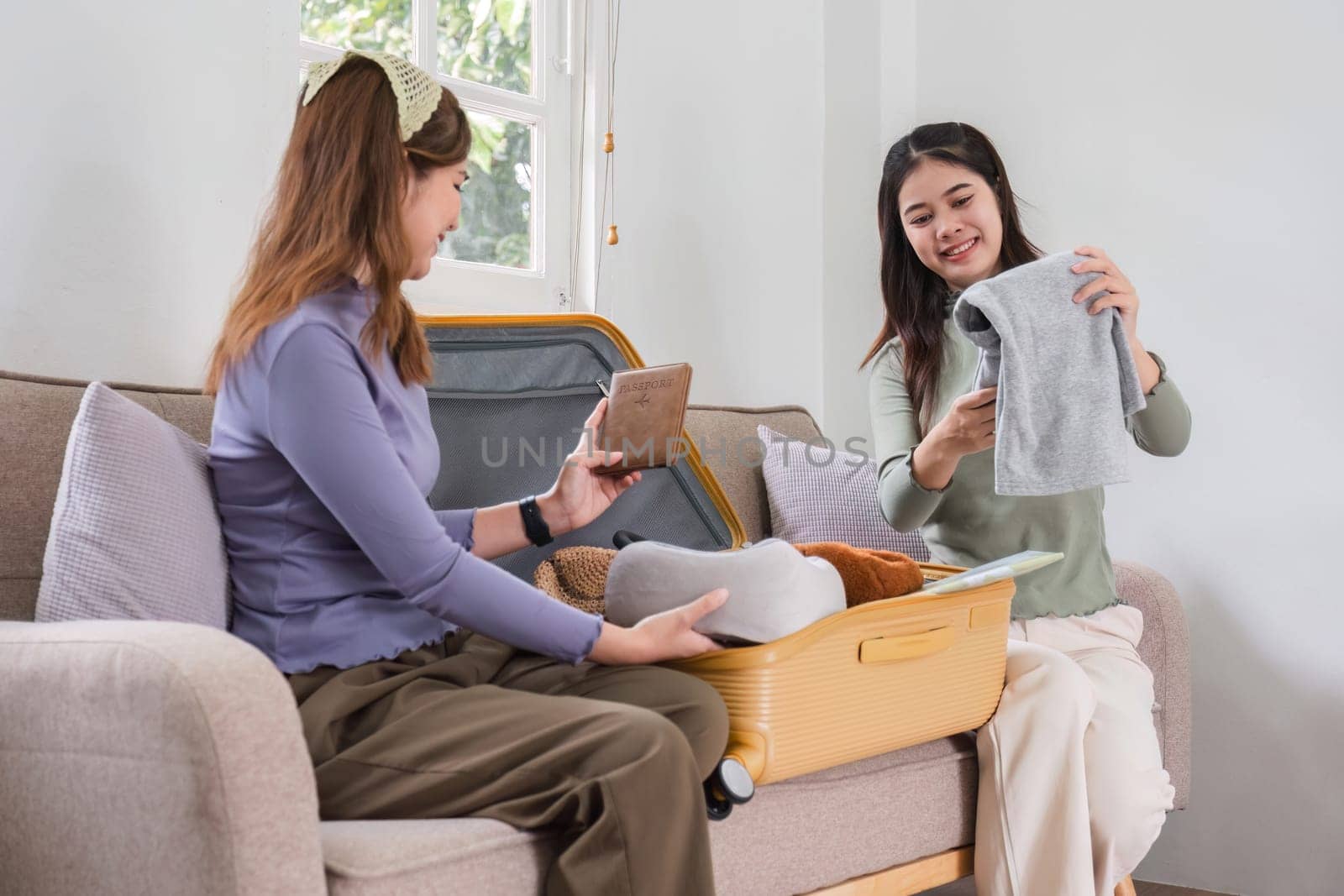 Two Asian female friends pack their suitcases and plan a vacation. Before going on vacation together by wichayada