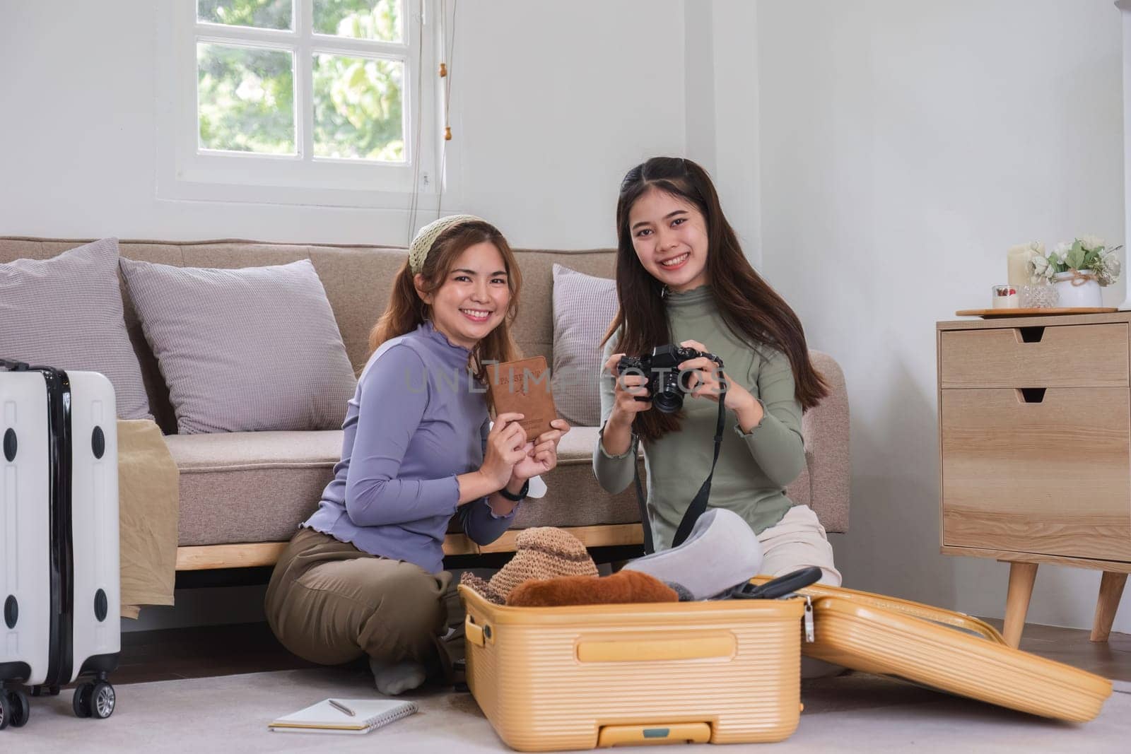 Two Asian female friends pack their suitcases and plan a vacation. Before going on vacation together by wichayada