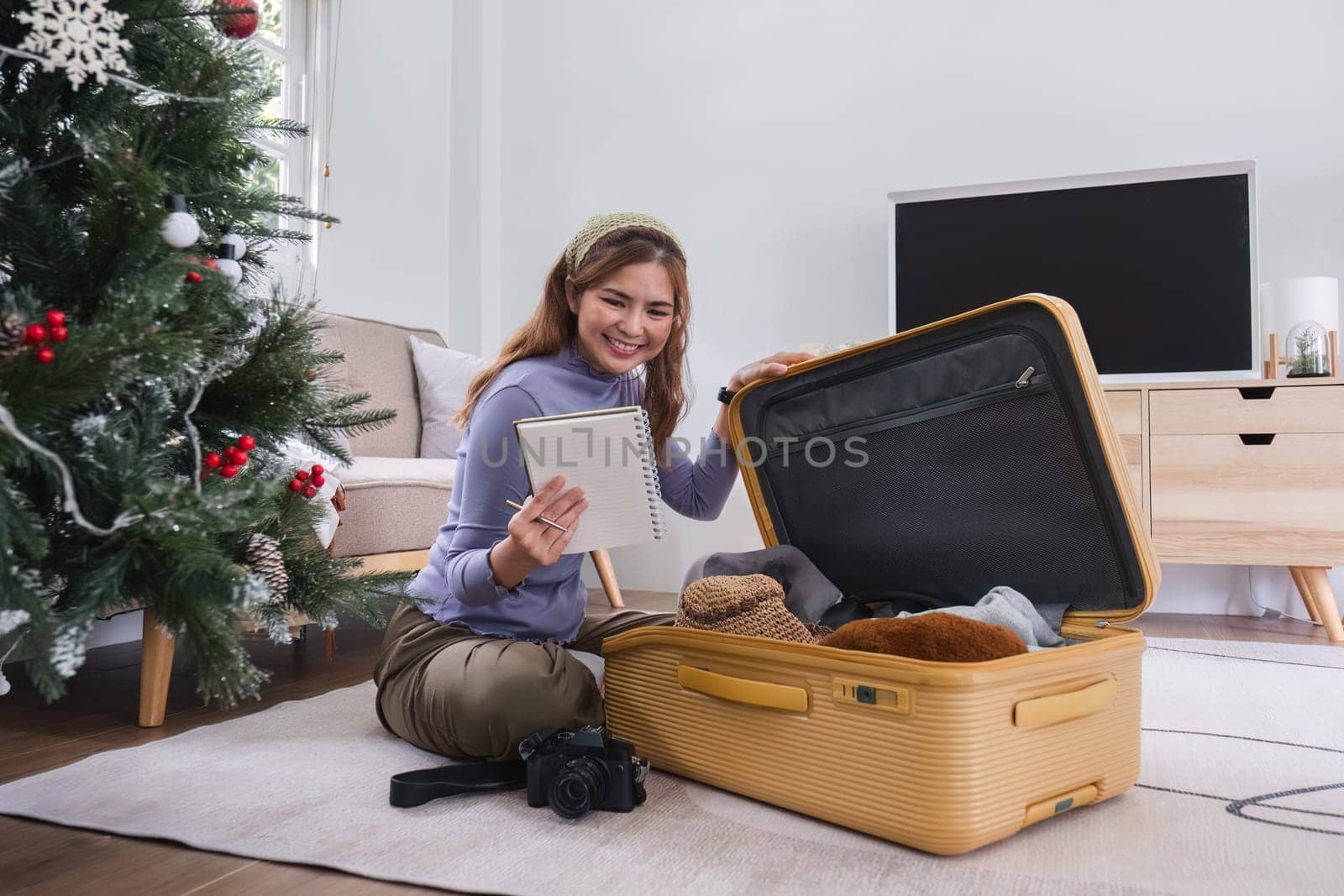 Attractive Asian woman packs her suitcase, packing her belongings, clothes and travel documents before going on vacation. Lifestyle concept.