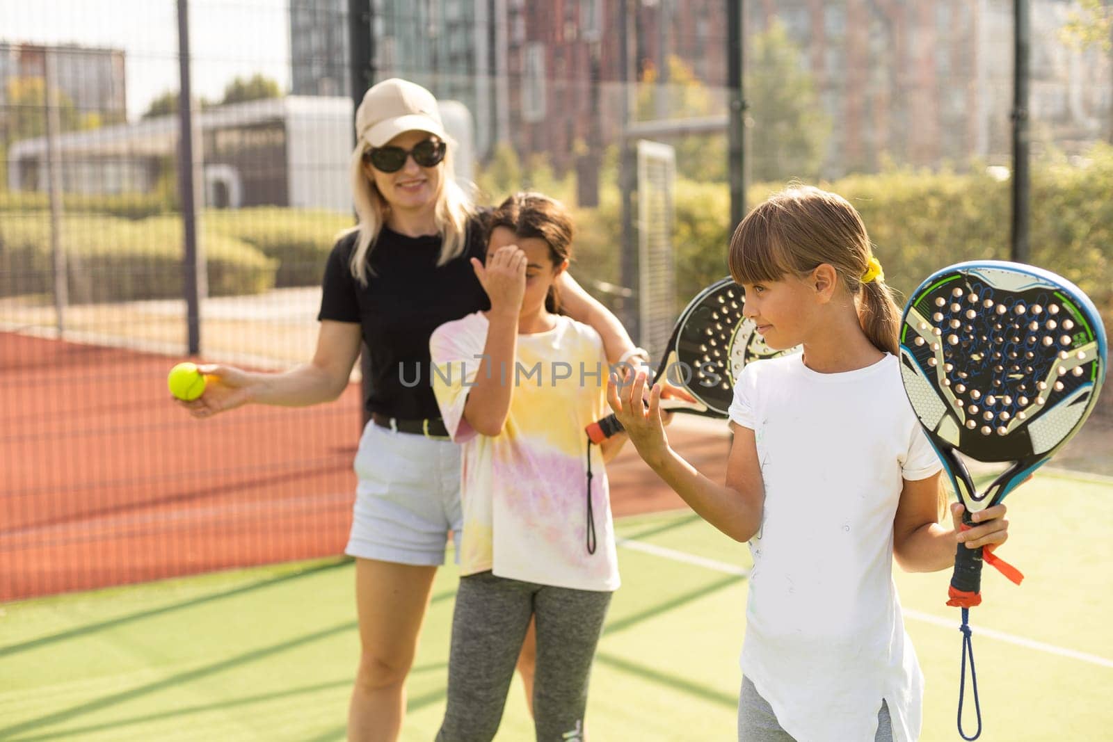 mother and daughters playing padel outdoor by Andelov13