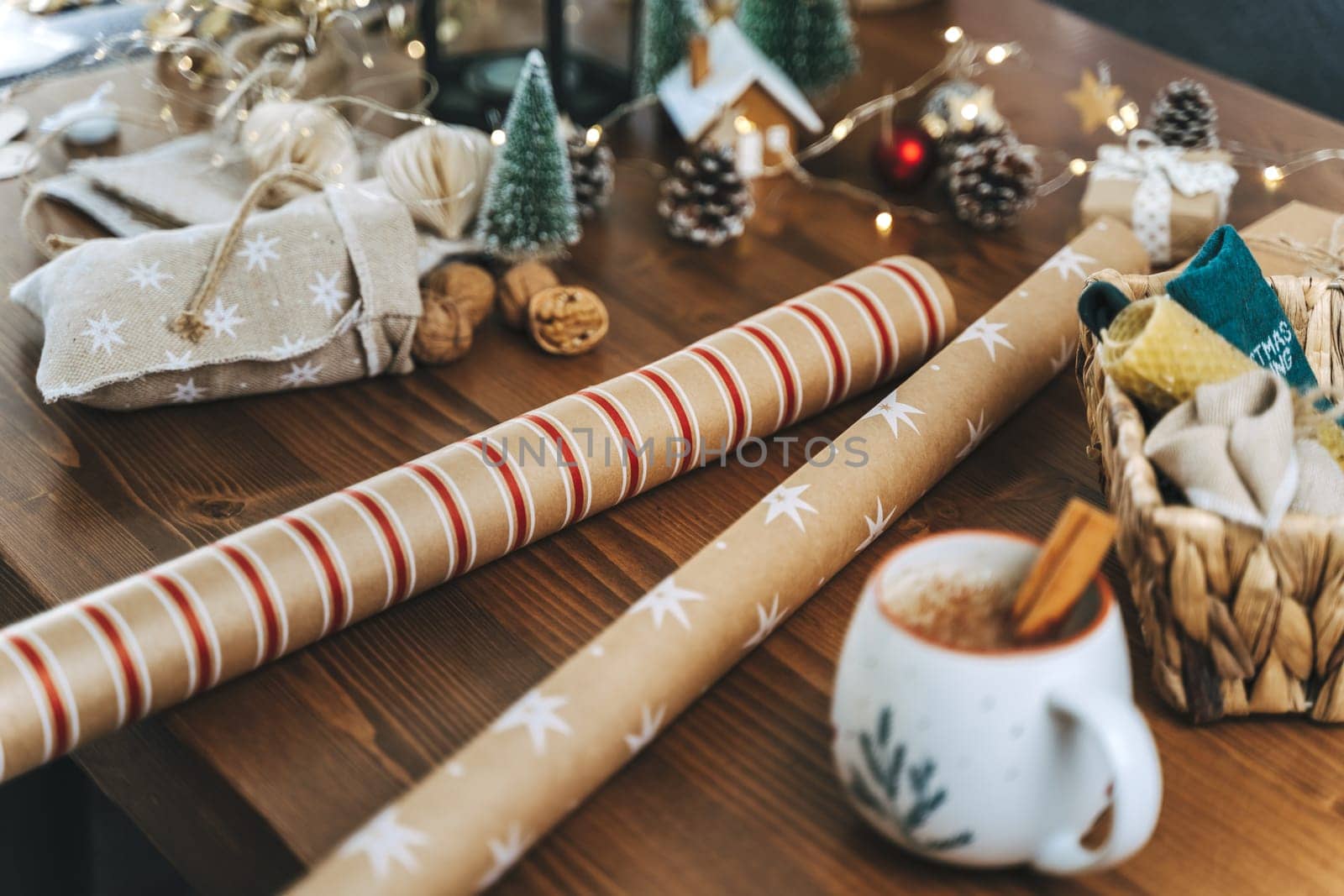Preparing Christmas eco gift. Wrapping paper, wicker basket, coffee cup. Unprepared presents on wooden table with natural decor elements and items Christmas packing wrapping Concept.