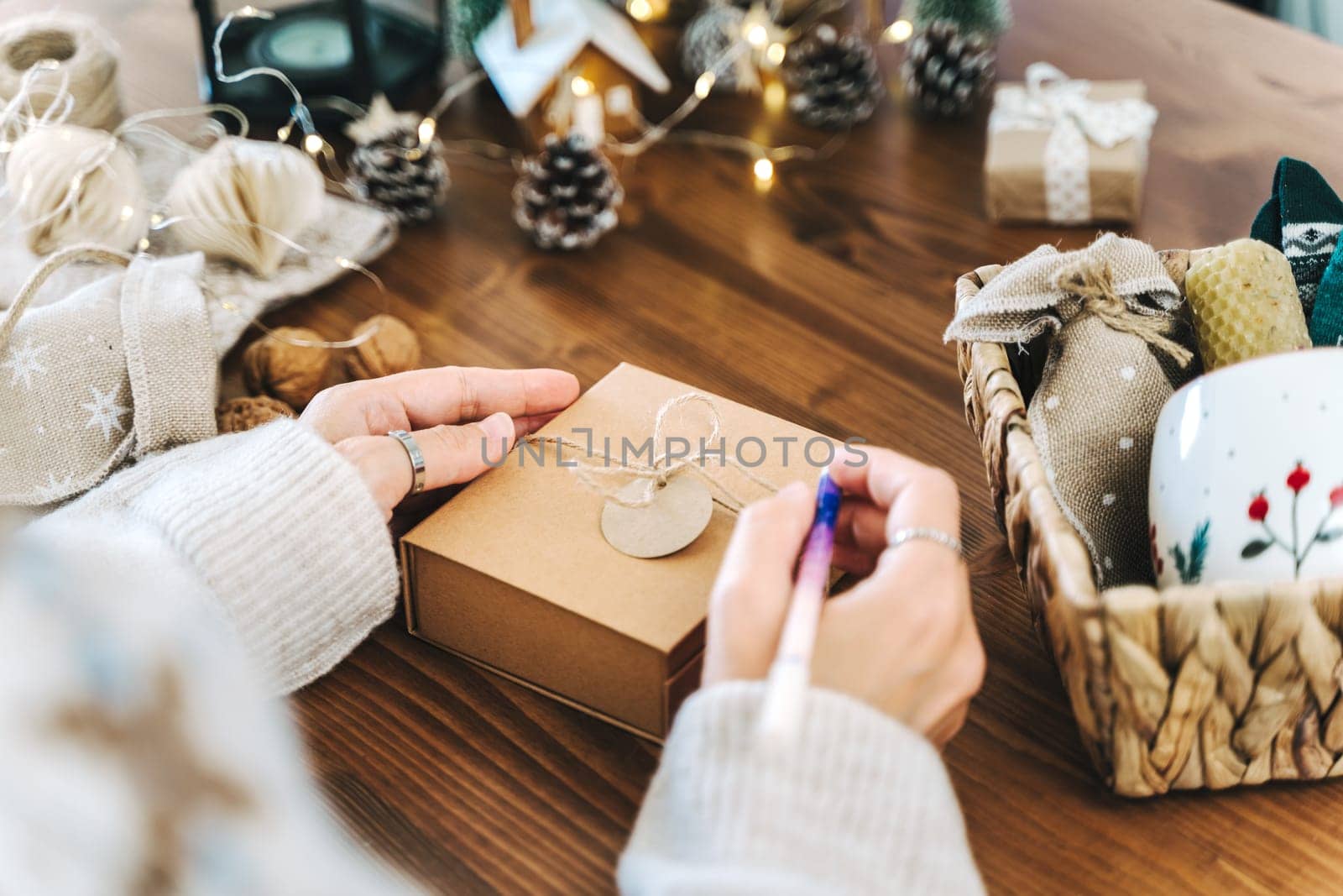 Woman s hands wrapping Christmas gift boxes, close up. Unprepared presents on white table with decor elements and items Christmas or New year DIY packing Concept by Ostanina