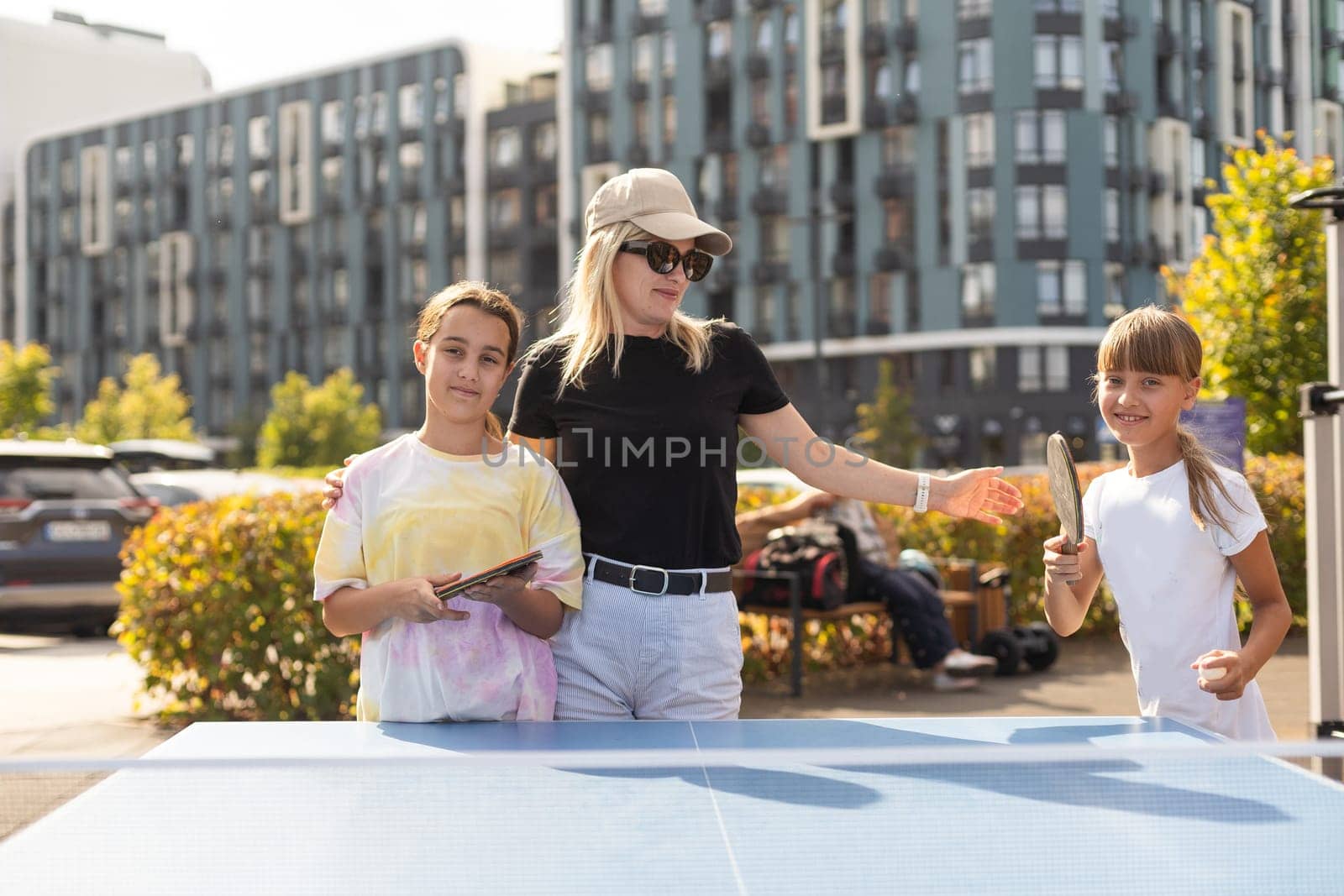 Family playing table tennis in the summer outdoors by Andelov13